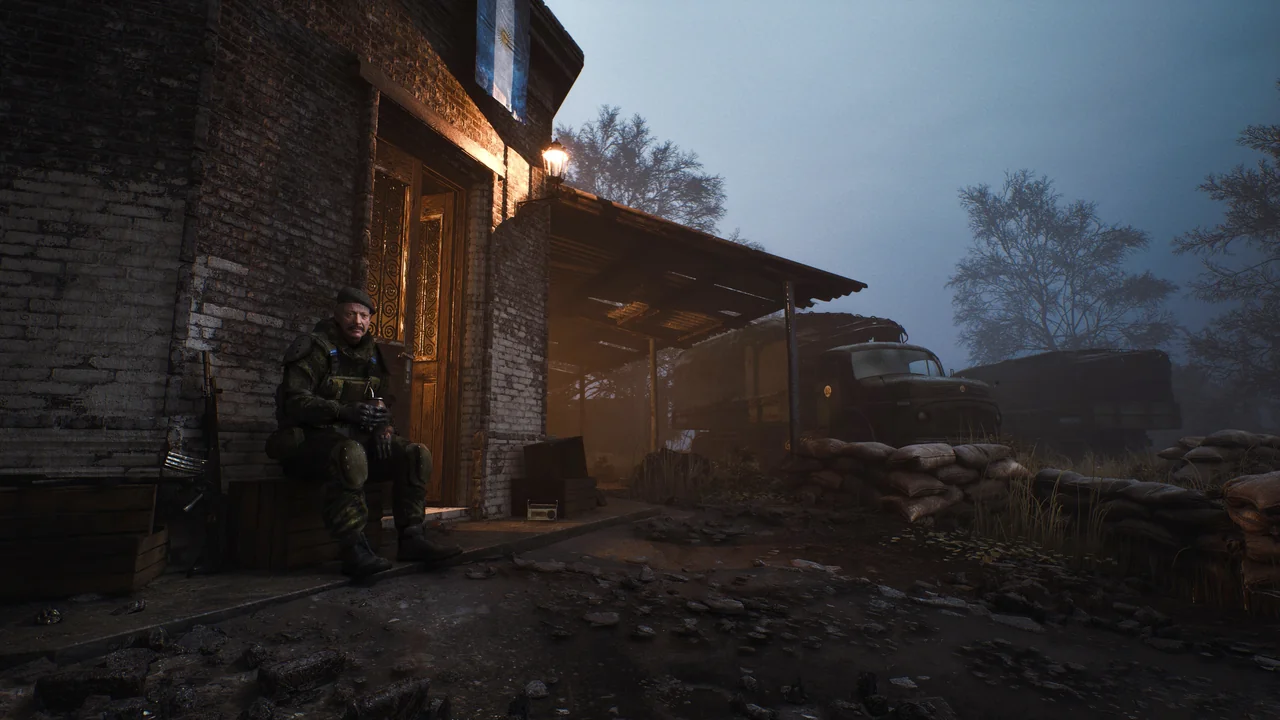 A survivor sits outside a lamplit outpost as dusk falls over a muddy road